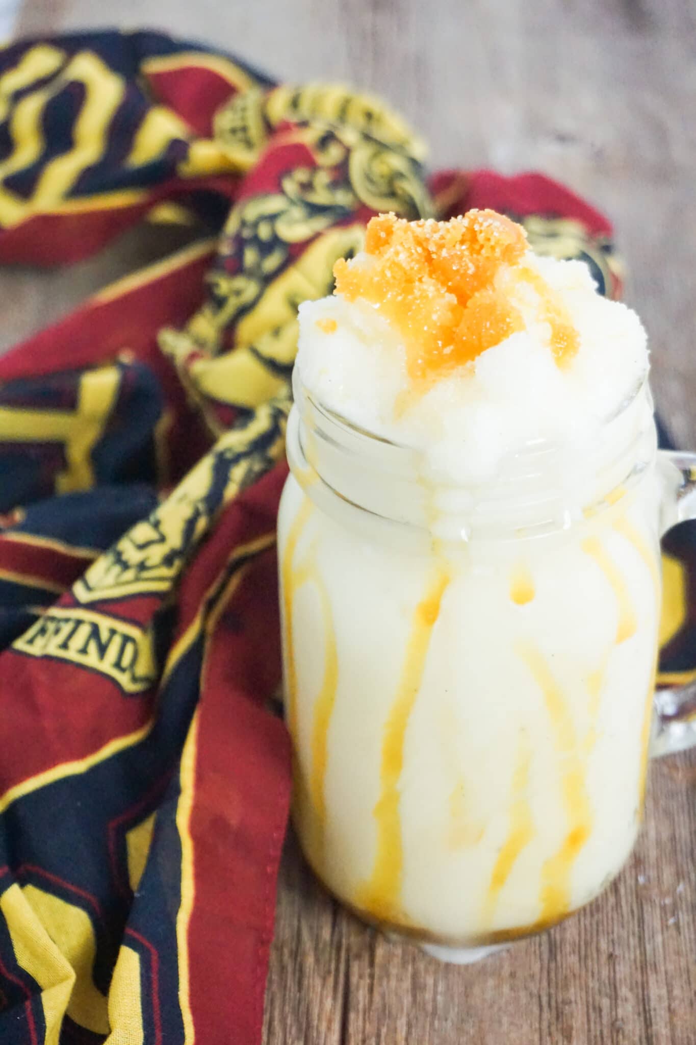 homemade butterbeer frappuccino in a glass next to a Harry Potter cloth