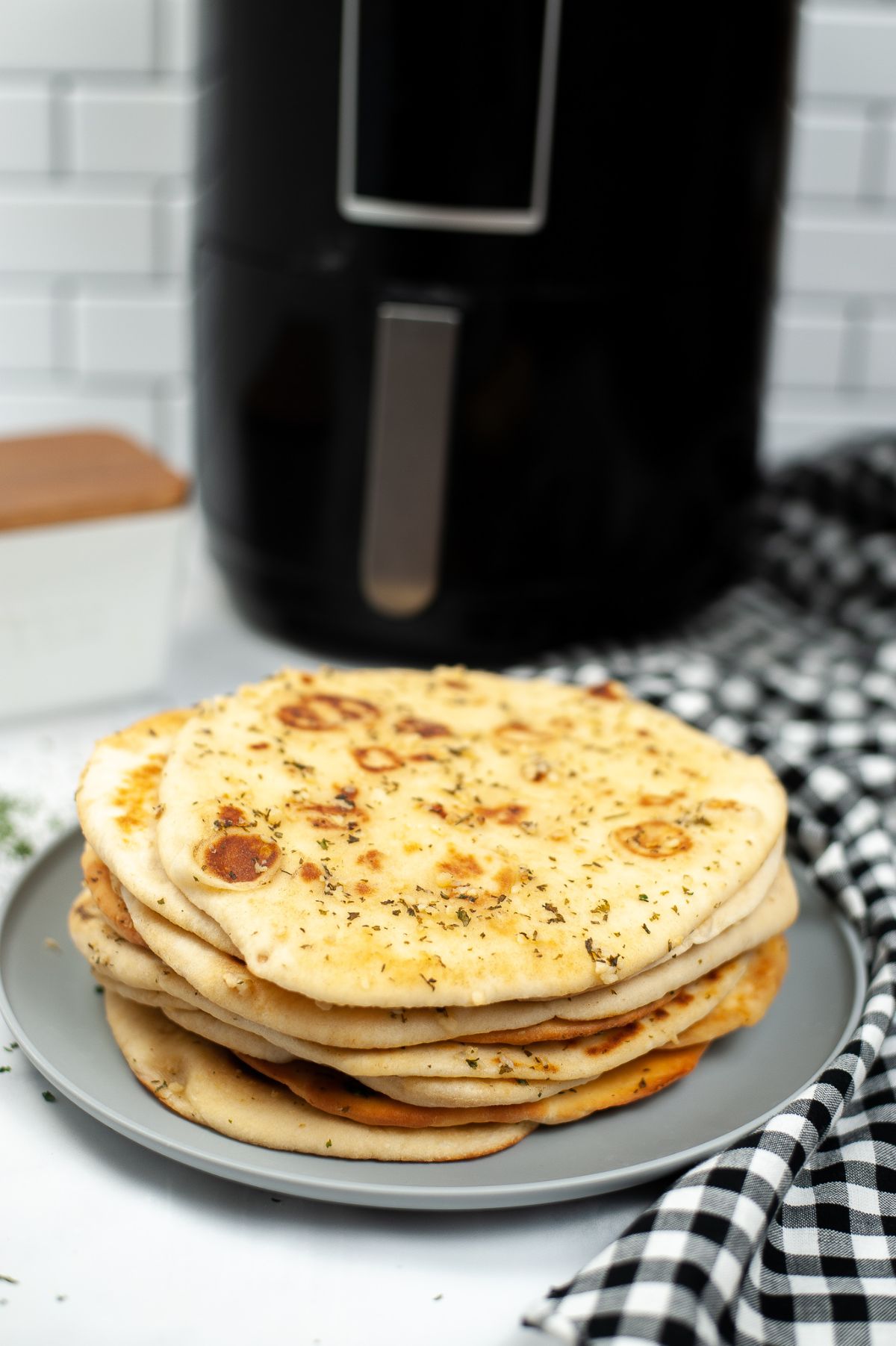 A stack of Air Fryer Naan on a gray plate with an air fryer in the background