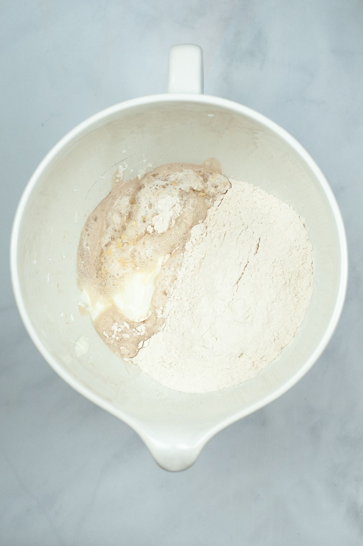 Dry yeast, water, and sugar combined in a mixing bowl.