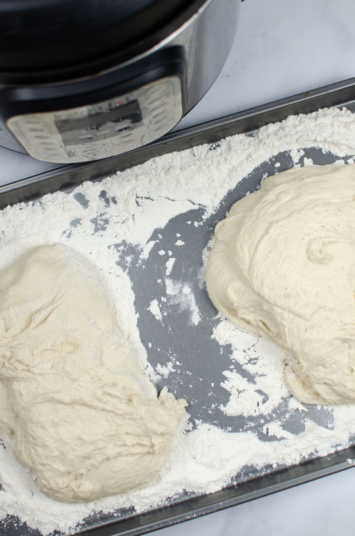 Dough separated in two portions on a floured baking pan.