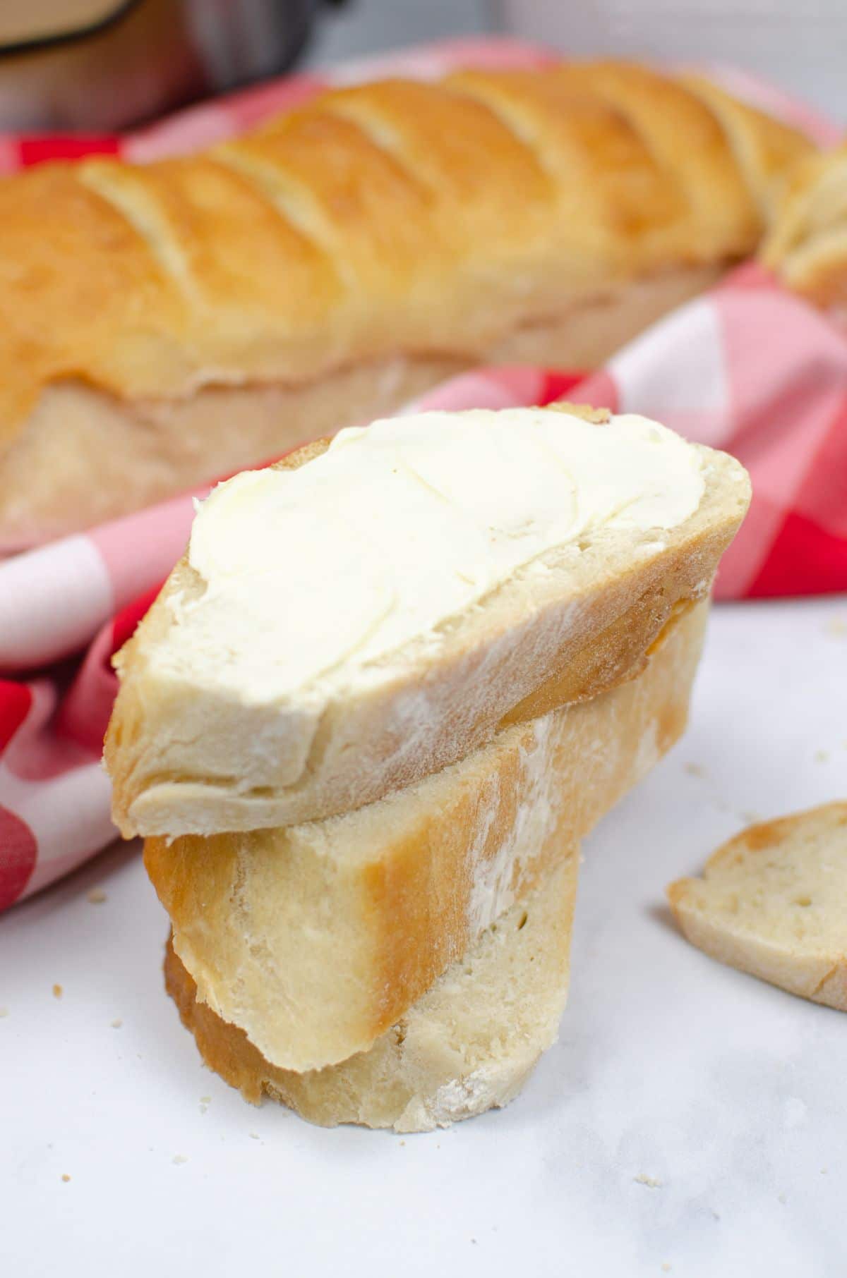 A stack of Instant Pot French Bread slices with the top most part covered with butter.