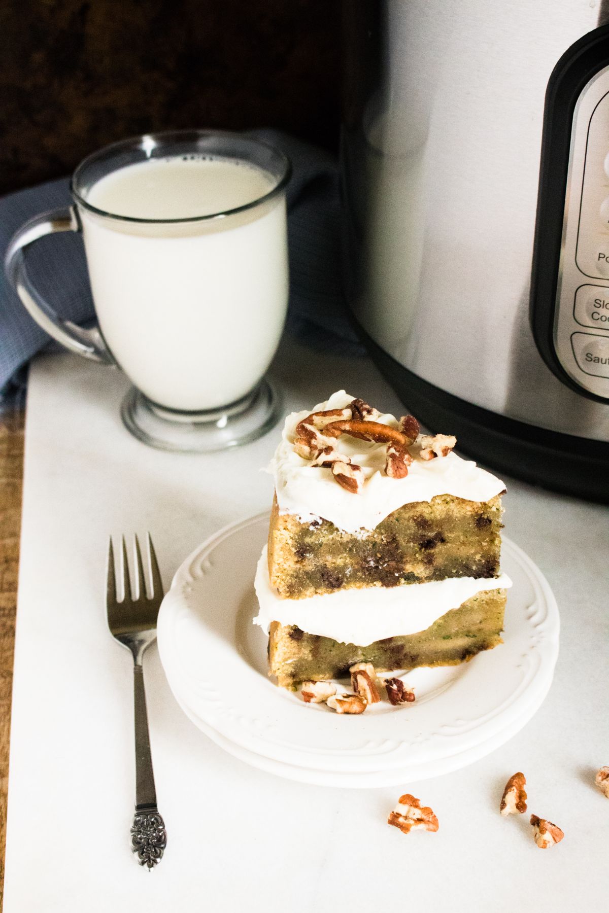 A slice of the Zucchini bread on a serving plate with a glass of milk in the background and a fork beside it.