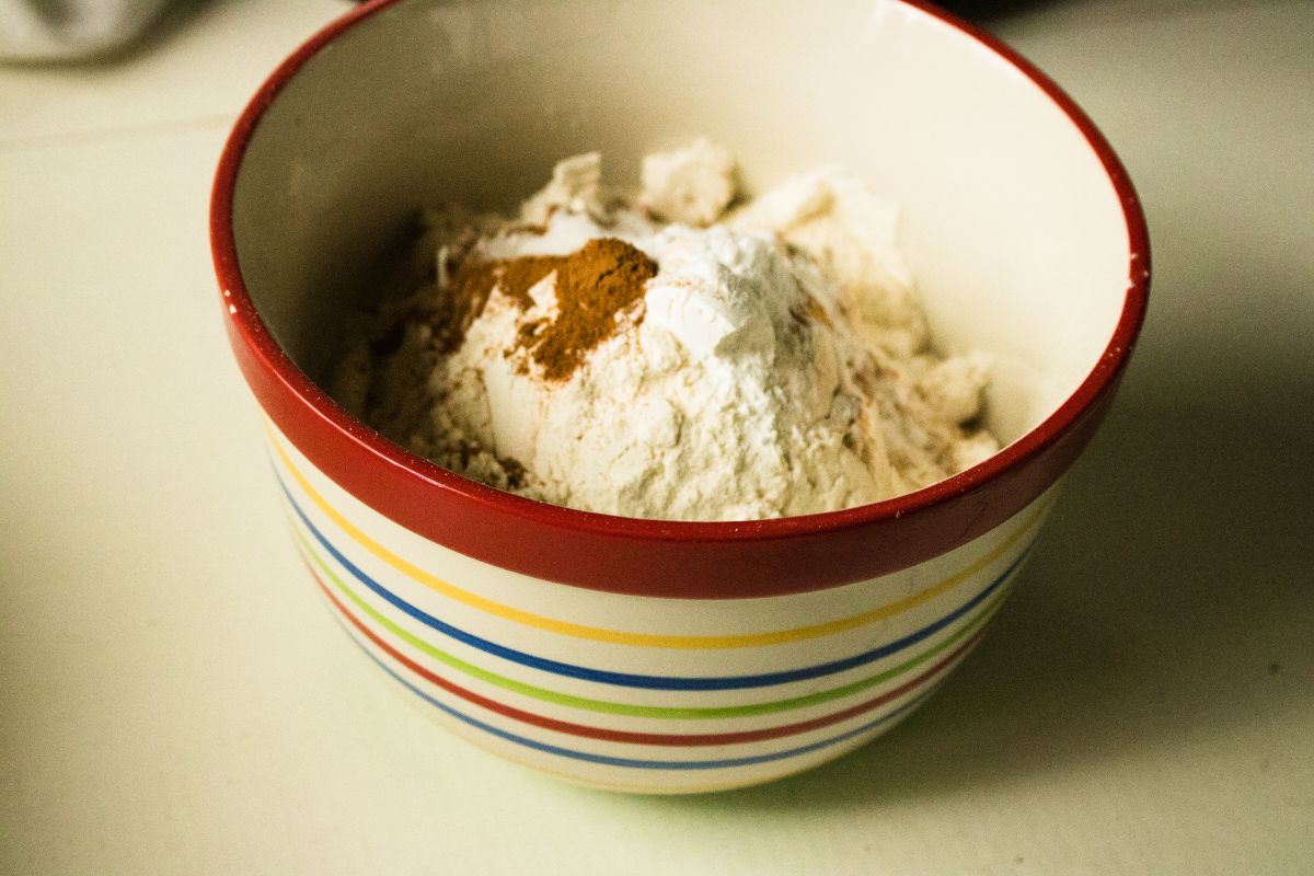 A bowl of combined dry ingredients: baking soda, baking powder, salt, flour, and cinnamon.