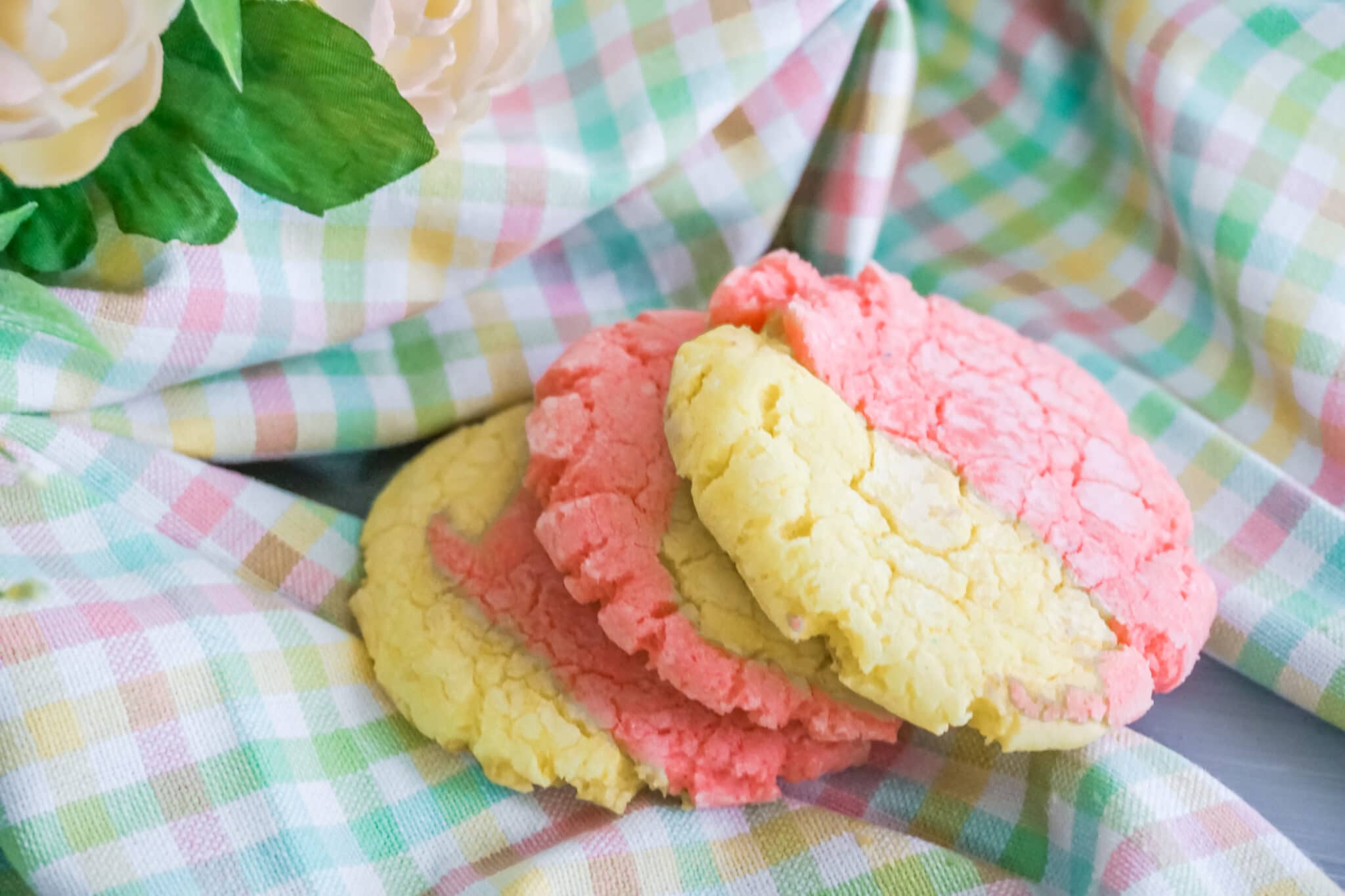 Strawberry Lemonade Crinkle Cookies on pastel colored plaid fabric next to a rose