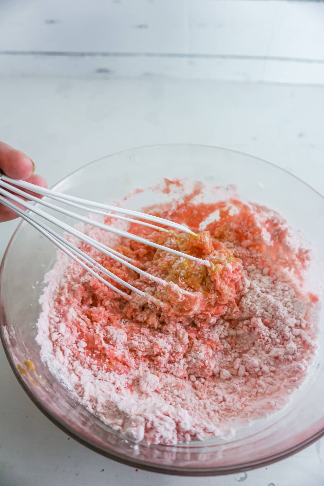 a whisk being used to stir cake mix in a glass bowl