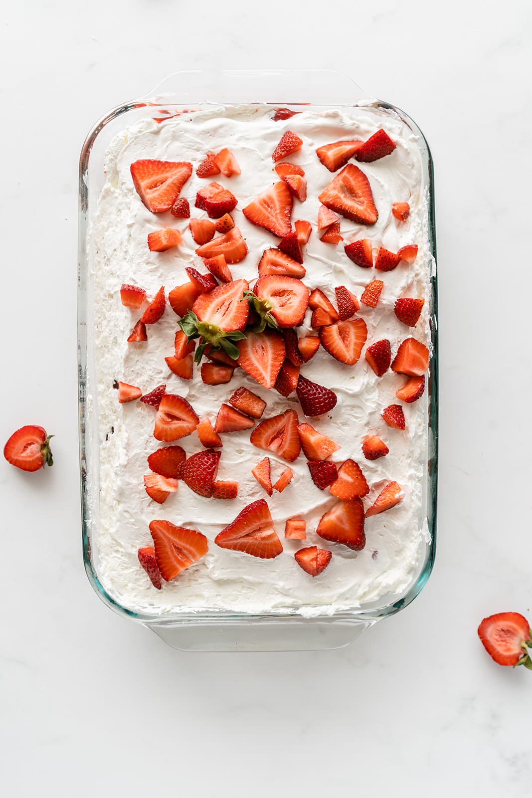 topping the cake with cool whip and sliced strawberries 