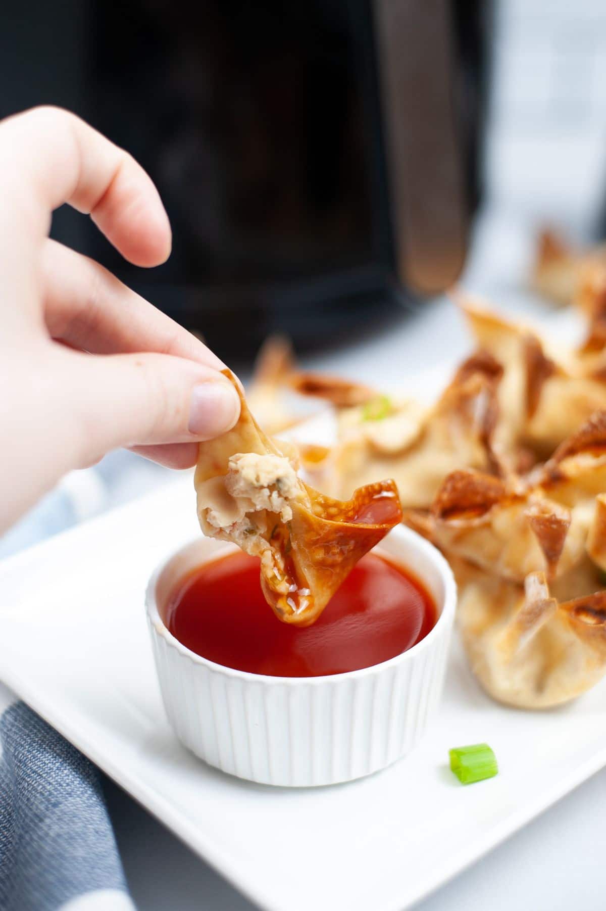 hand dipping the wonton into the dip 