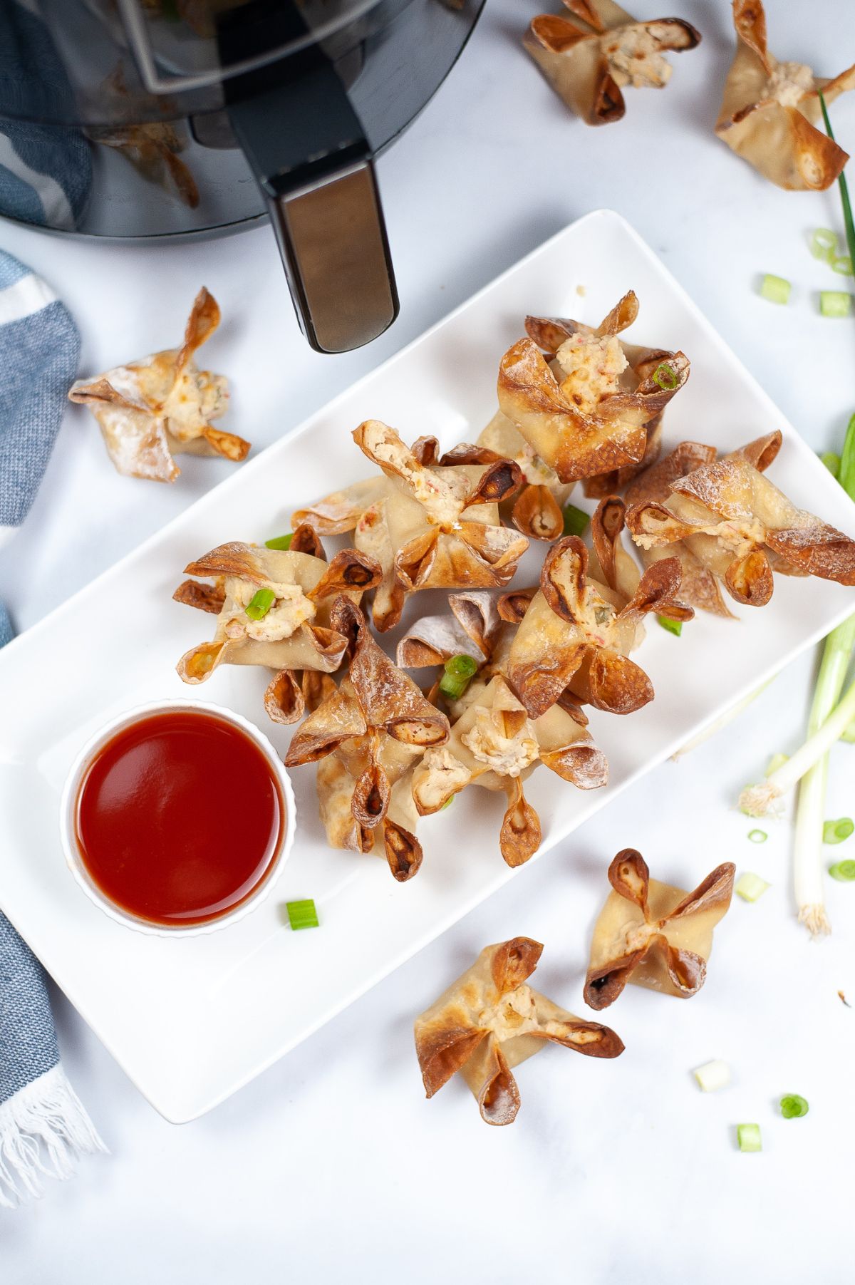 overhead view of a plate full of crab rangoon with dipping sauce 