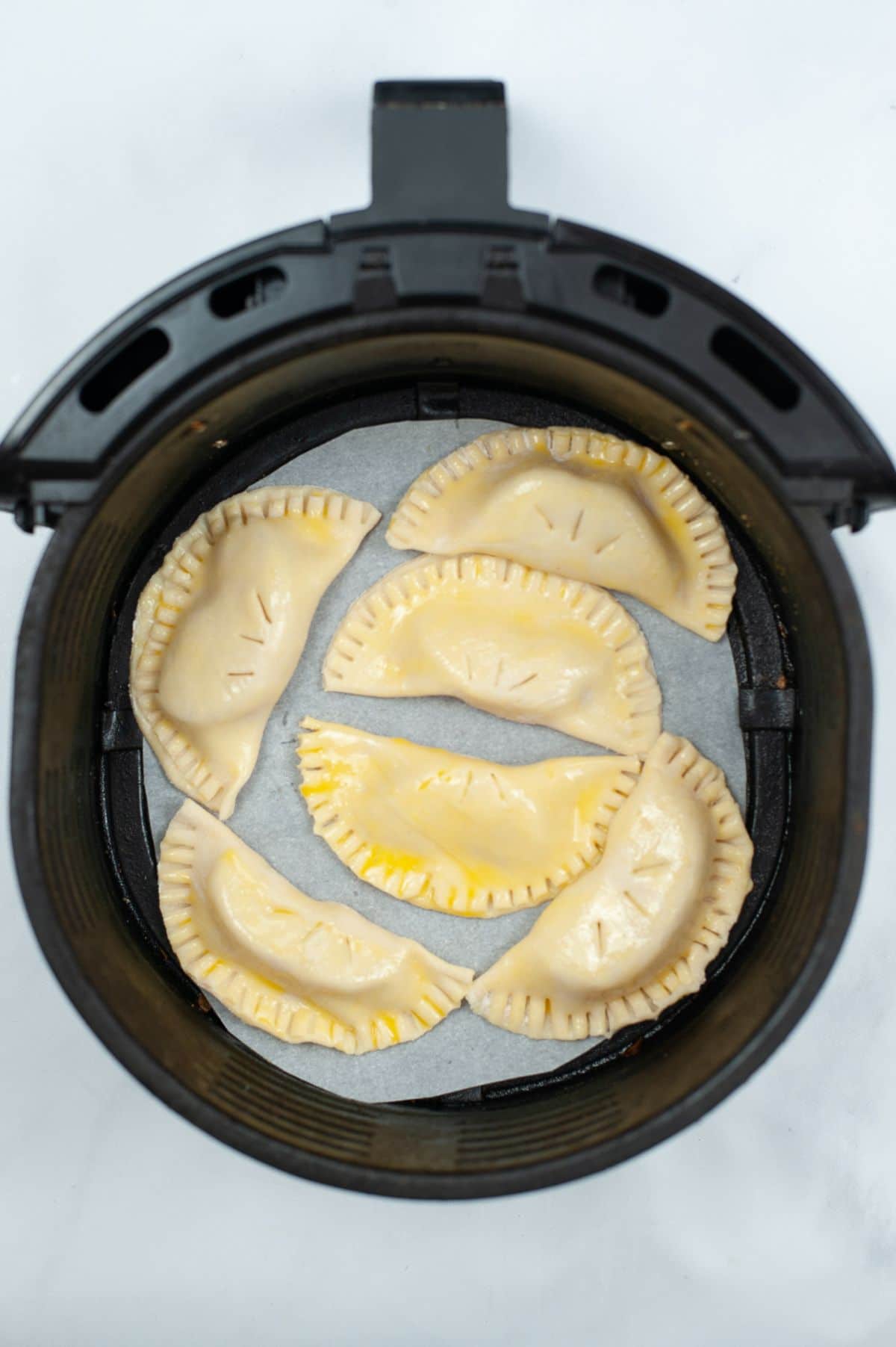 Air Fryer Caramel Empanadas on an air fryer basket, pre-cooking.