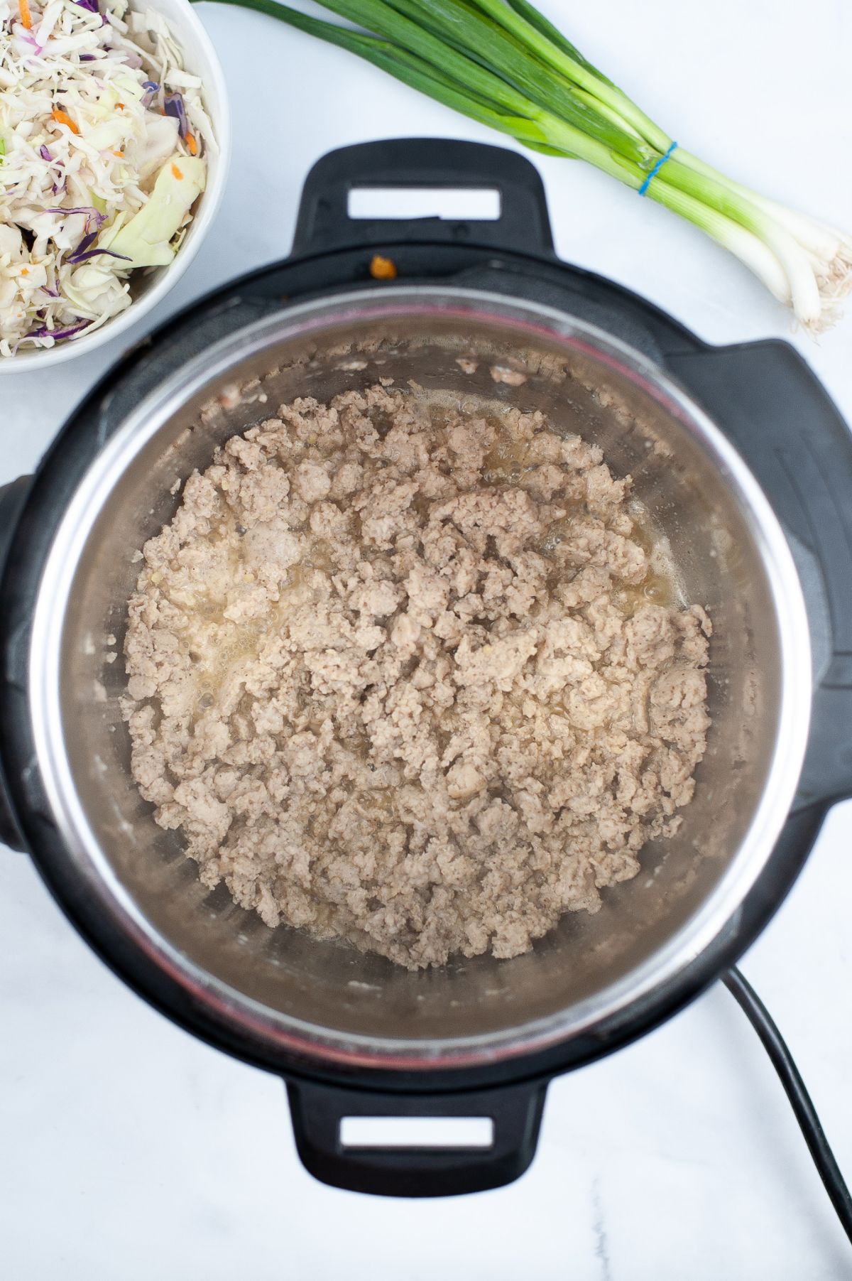 Ground chicken being cooked in an Instant Pot until it turns brown.