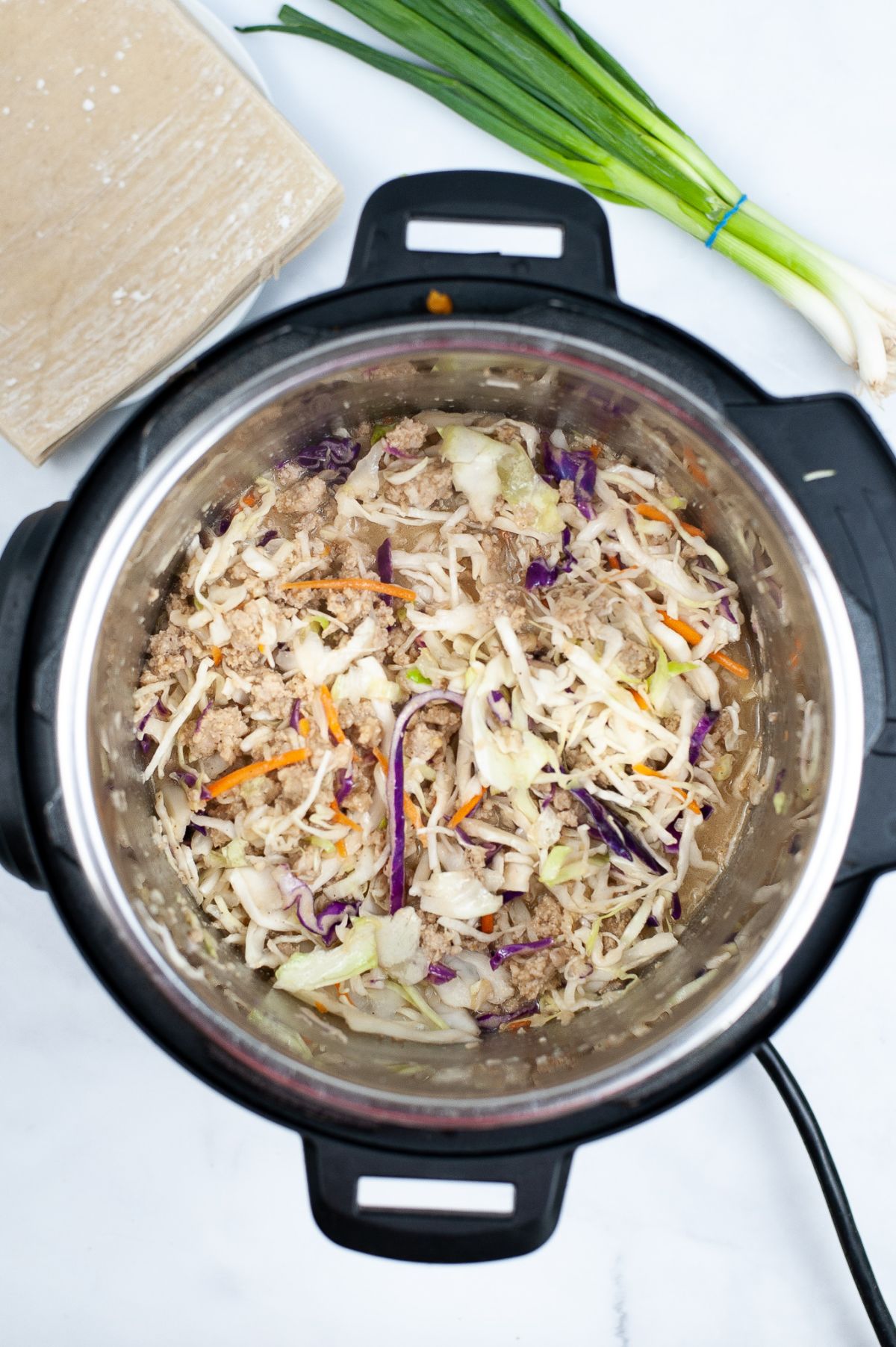 Seasoned ground chicken topped with coleslaw being cooked in Instant Pot.