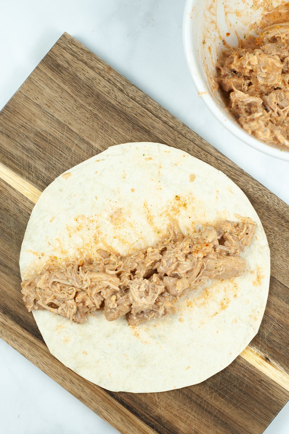 Flattened tortilla wrap with the chicken mixture on the center.
