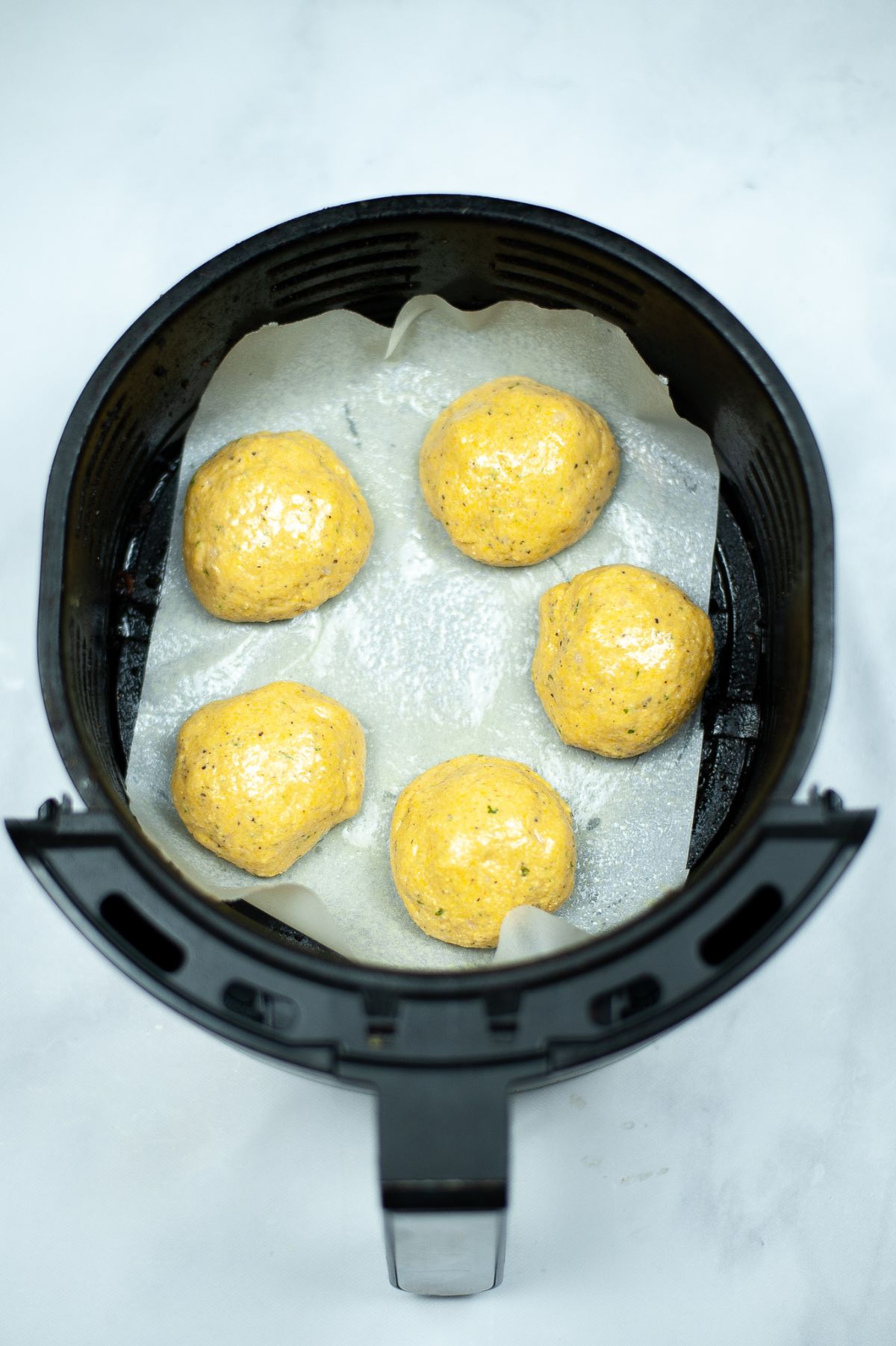 Shaped Air Fryer Hush Puppies in an air fryer basket ready for cooking.