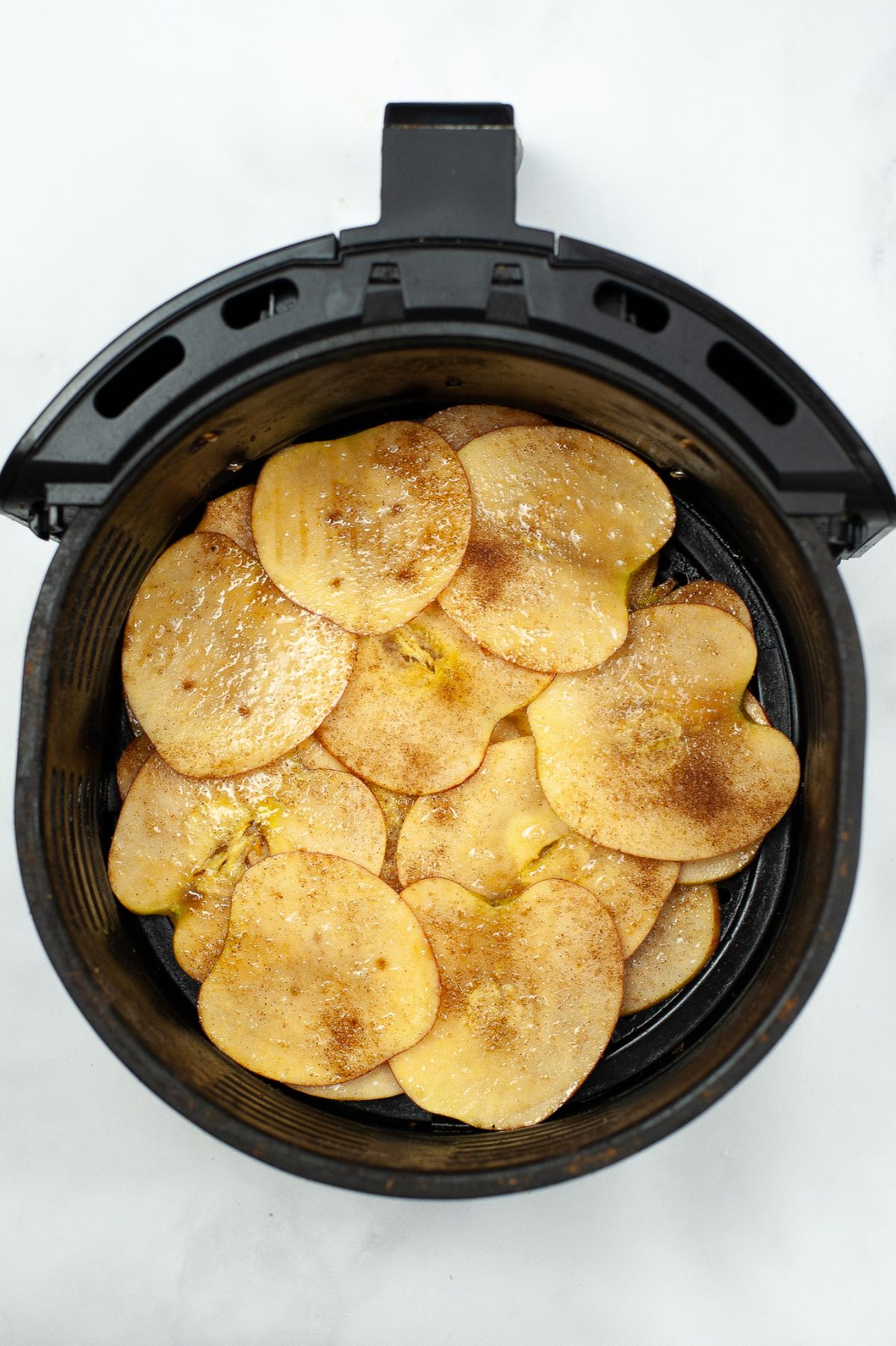 Cooked Air Fryer Cinnamon Apple Chips in an air fryer basket.