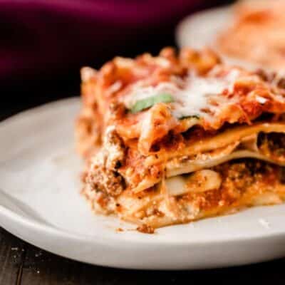 A classic lasagna recipe consisting of layers of tender ground beef and rich tomato sauce, served elegantly on a rustic wood table.