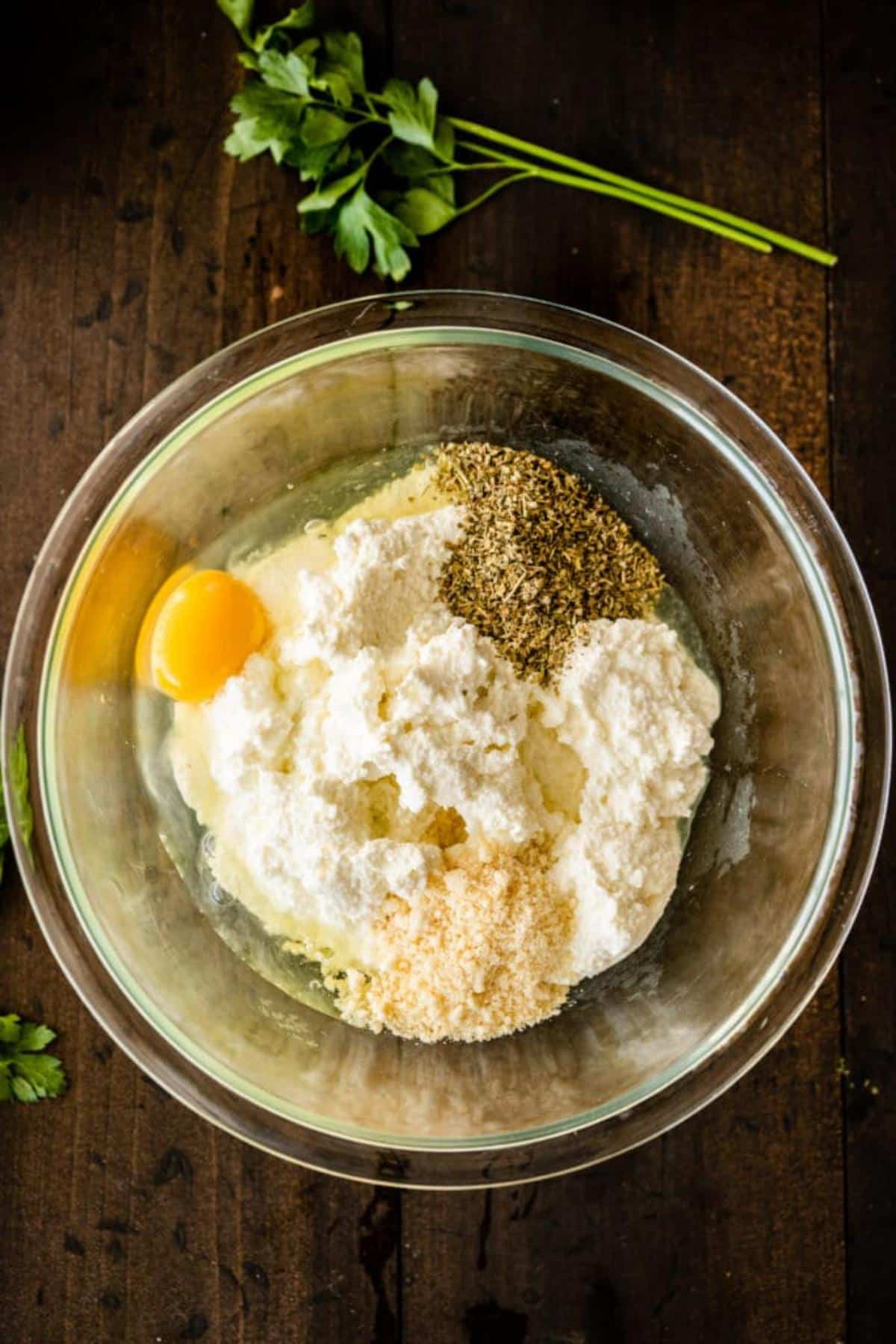 Cheese, egg and spices for lasagna in a mixing bowl.