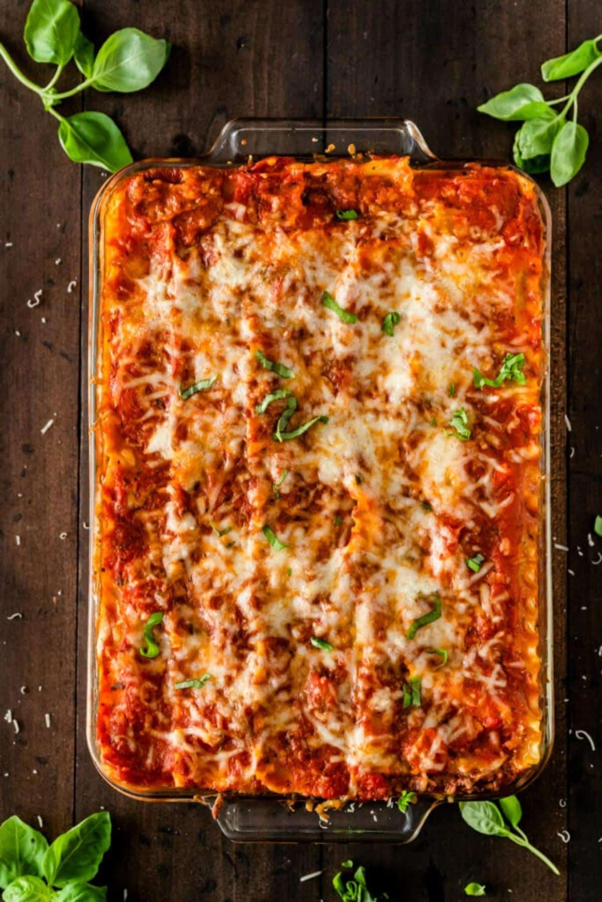 Homemade Lasagna Recipe with Ground Beef in a glass dish on a wooden table.