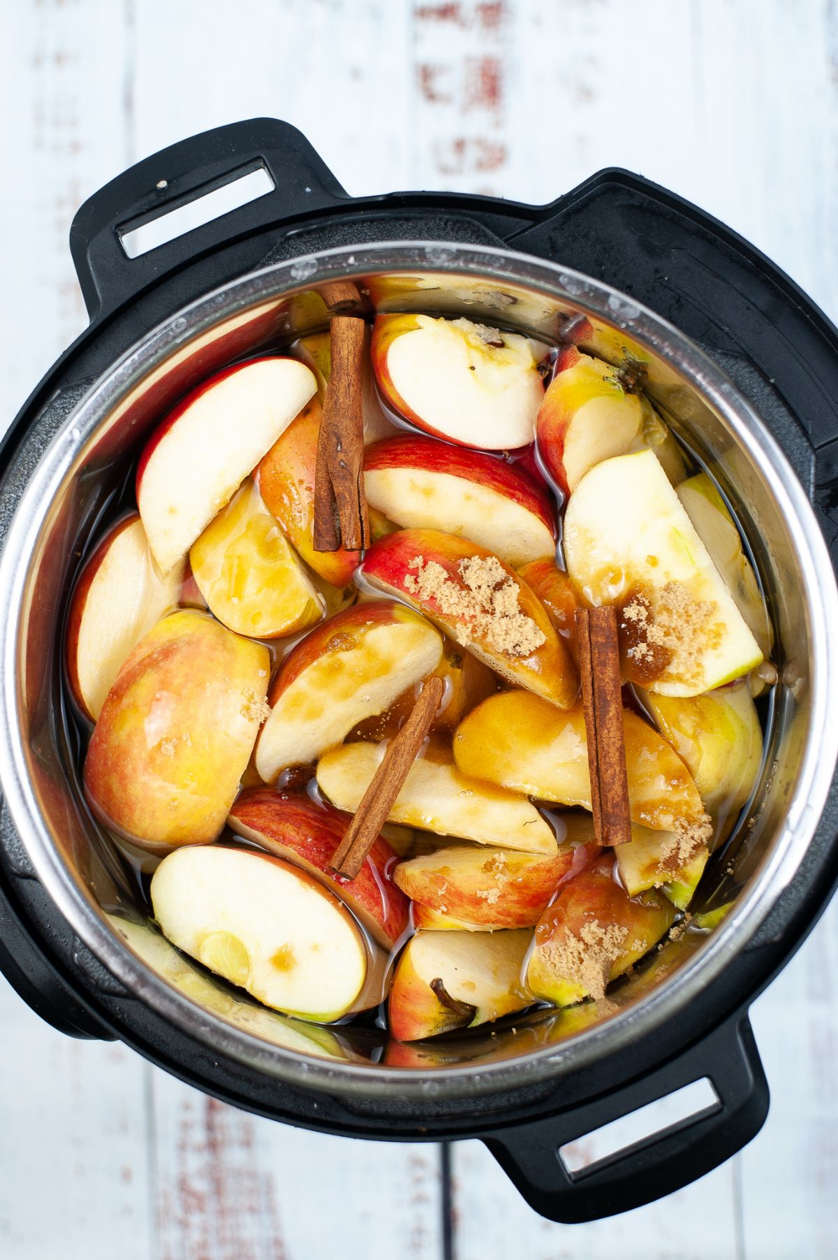 Sliced apples, cinnamon barks, sugar and water in an Instant Pot.