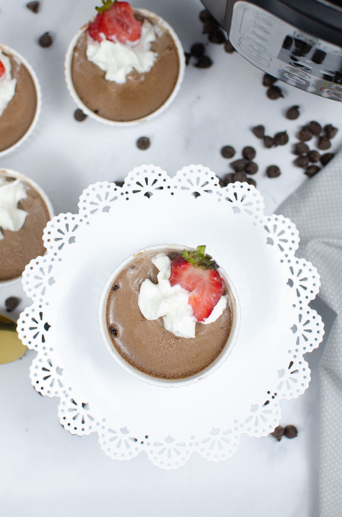 An overhead vertical shot of  Instant Pot Chocolate Mousse in a white ramekin placed at the center of a white circular cake stand.