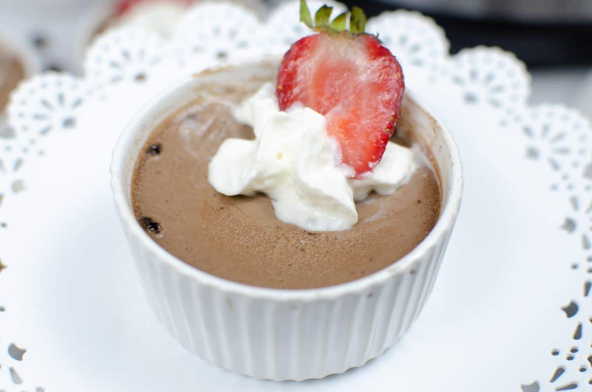  Instant Pot Chocolate Mousse in a white ramekin topped with cream and sliced strawberry toppings.