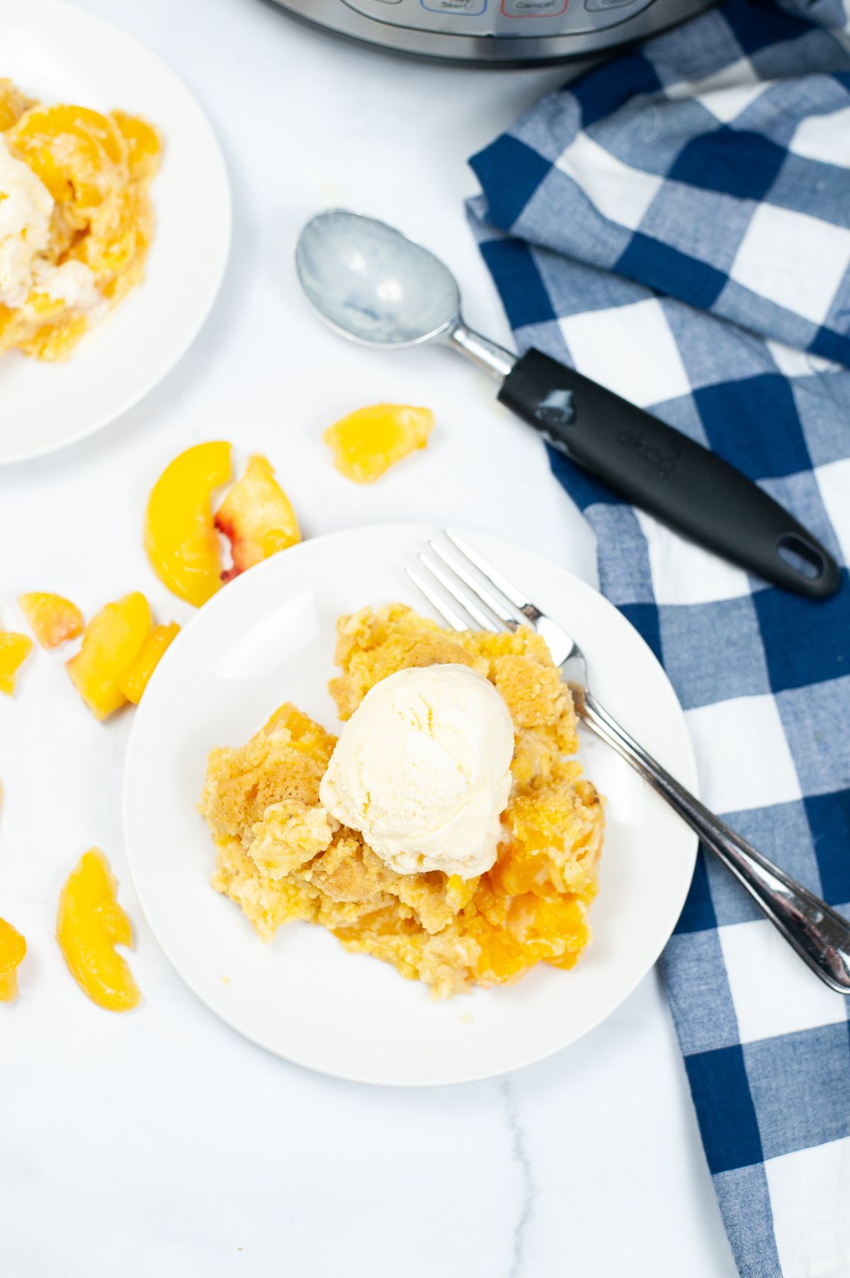 A vertical overhead shot of Instant Pot Peach Cobbler  topped with ice cream on white serving plate.