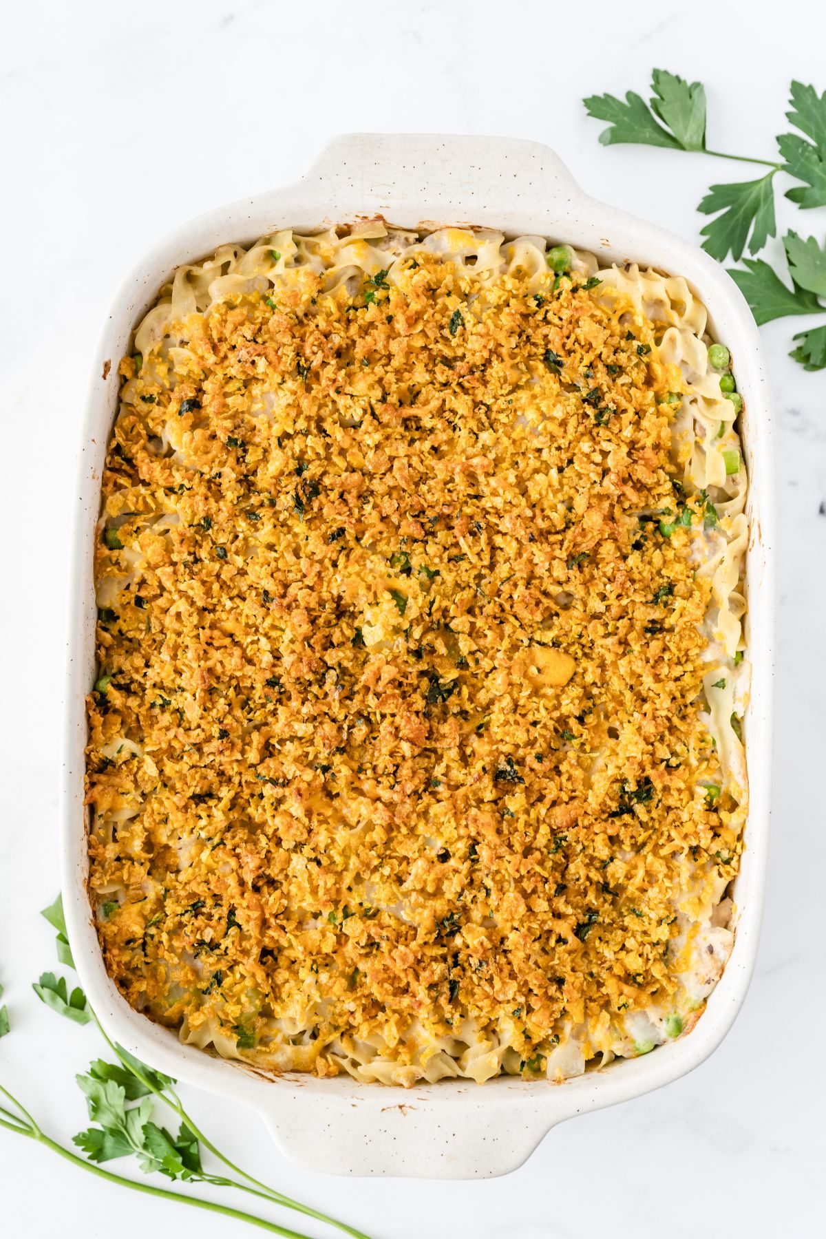 A baking pan with the noodle mixture topped with the buttery cornflake topping.
