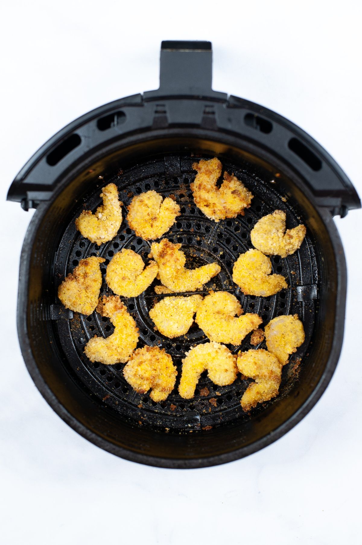 Cooked shrimp in an air fryer basket.