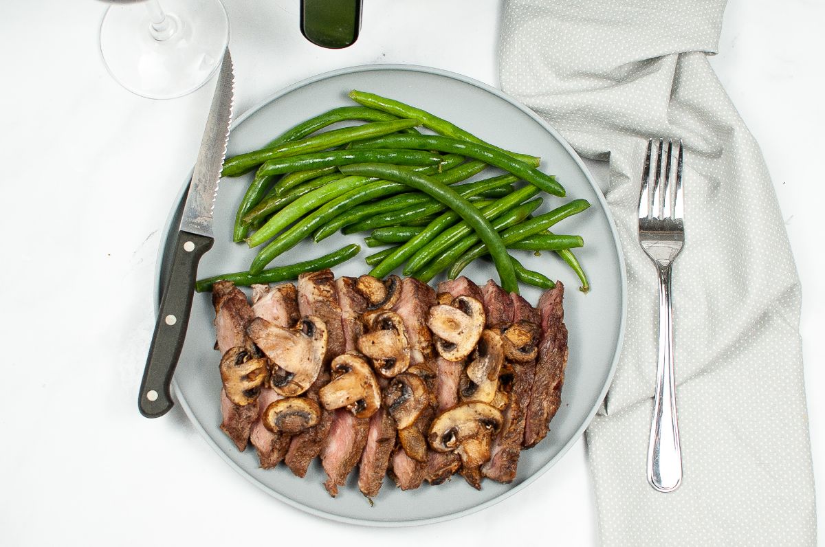 Horizontal overhead image of Air Fryer Steak and Mushrooms on a light blue serving plate with <a href=