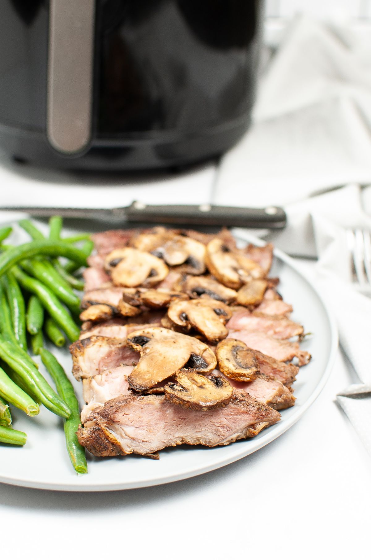 Vertical image of Air Fryer Steak and Mushrooms on a white serving plate with <a href=