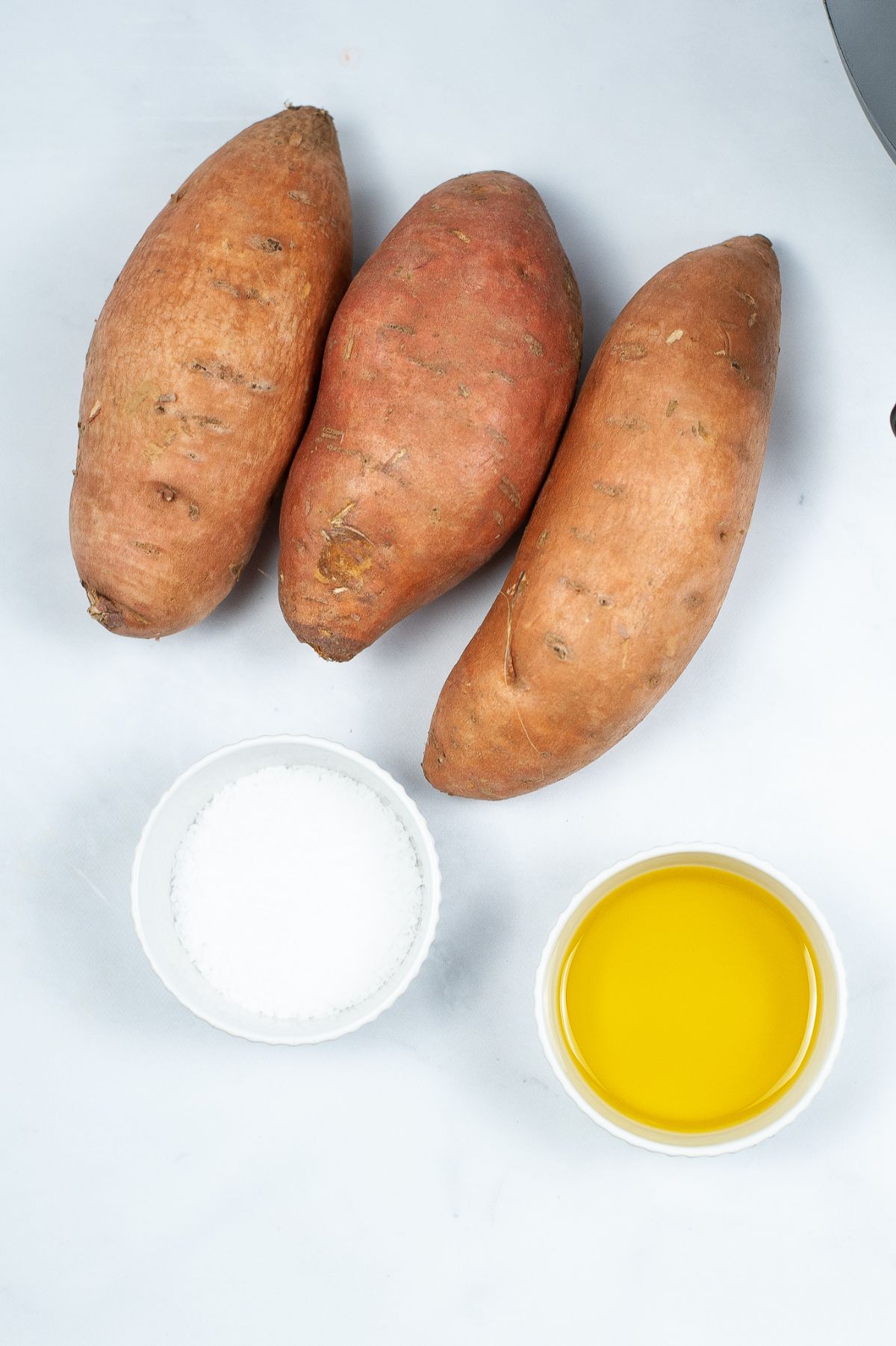 Ingredients used to make an Air Fryer Potato Fries such as sweet potatoes, course salt, and olive oil.