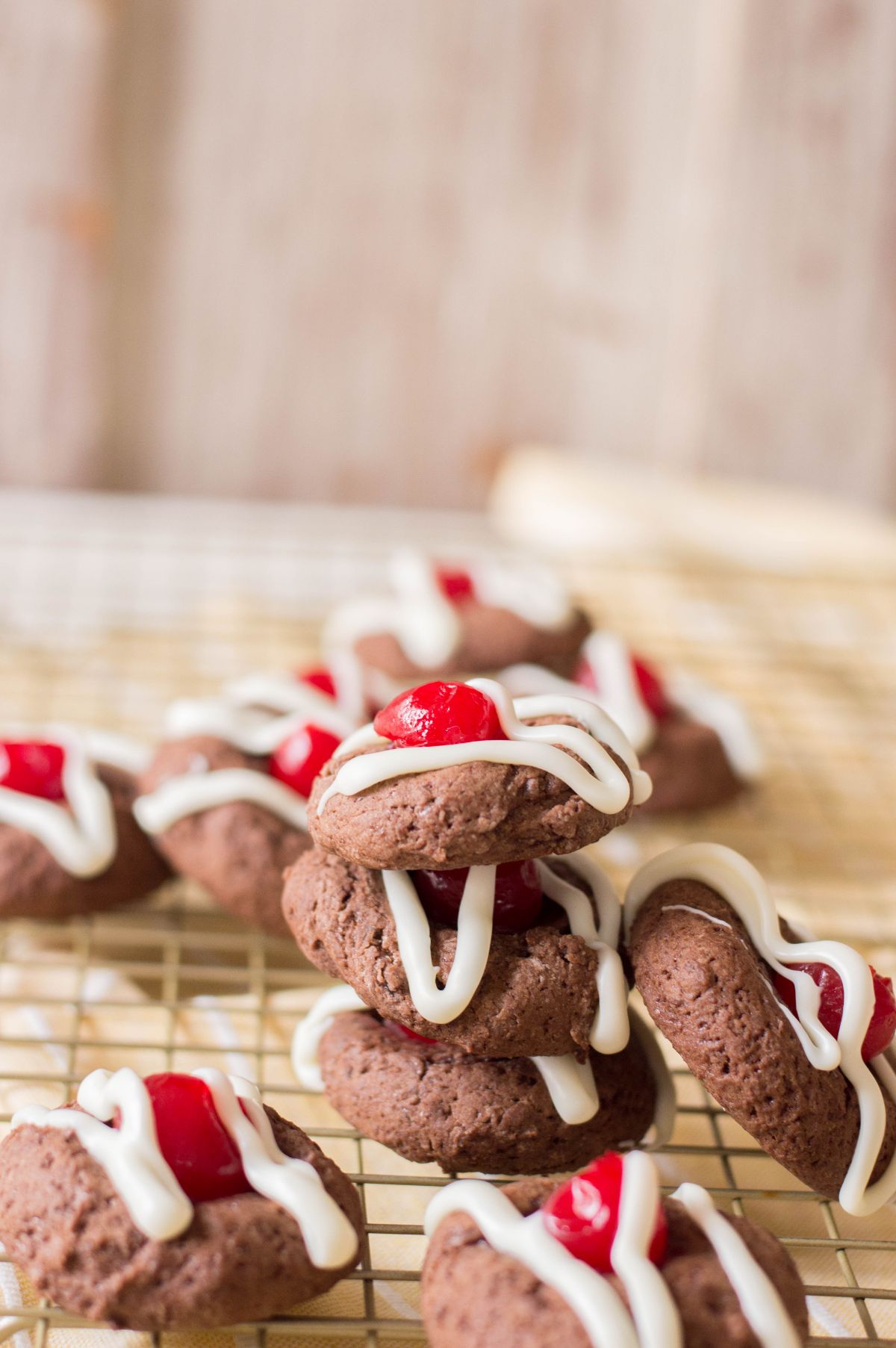 Vertical image of stacked Chocolate Cherry Cookies on a drying rack.