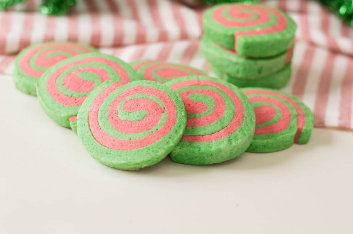 A horizontal image of Christmas Pinwheel Cookies slightly stacked like a fallen domino tiles showcasing the red and green swirls.