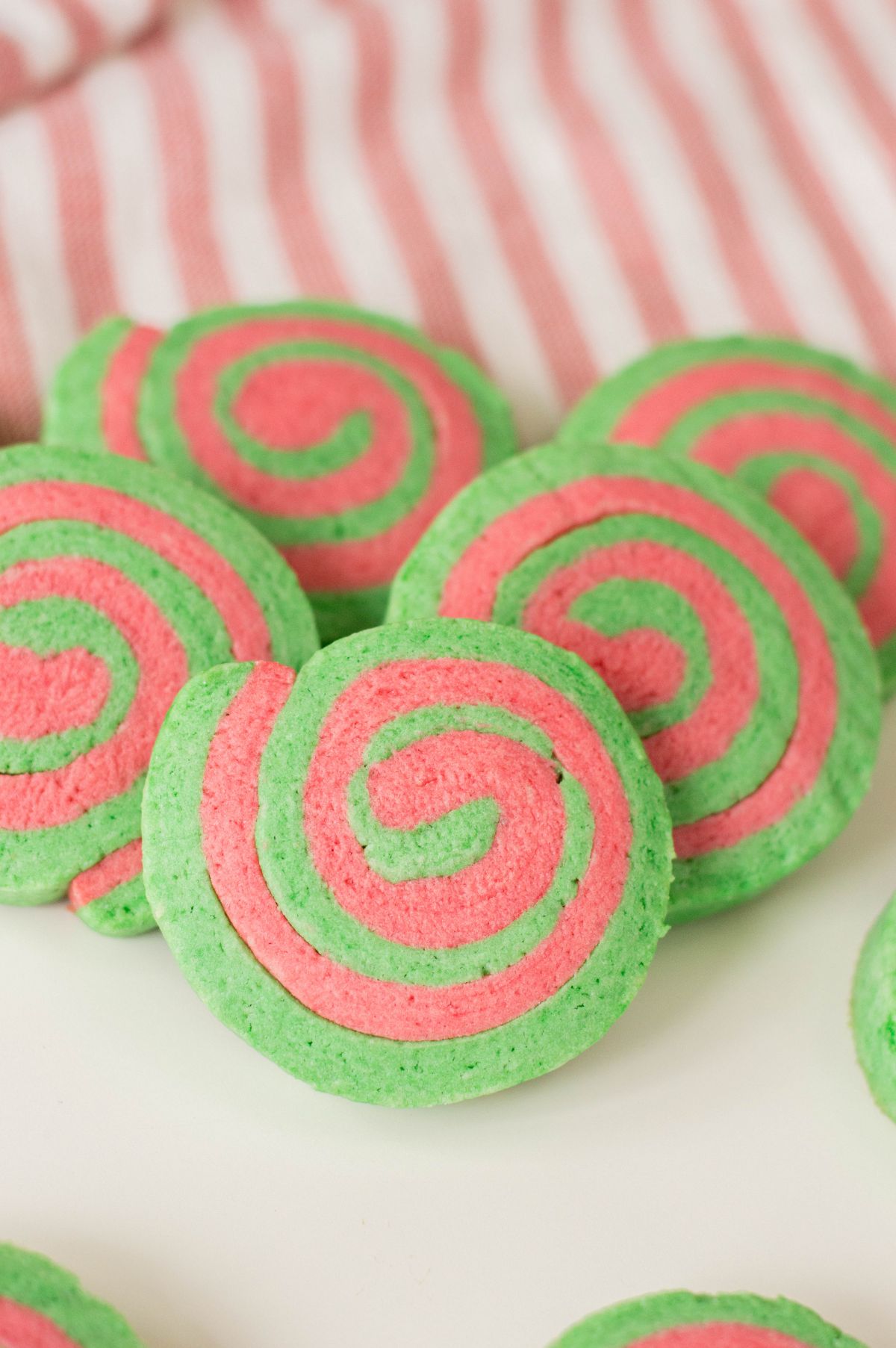 A vertical image of Christmas Pinwheel Cookies slightly stacked on each other showcasing the red and green swirls.