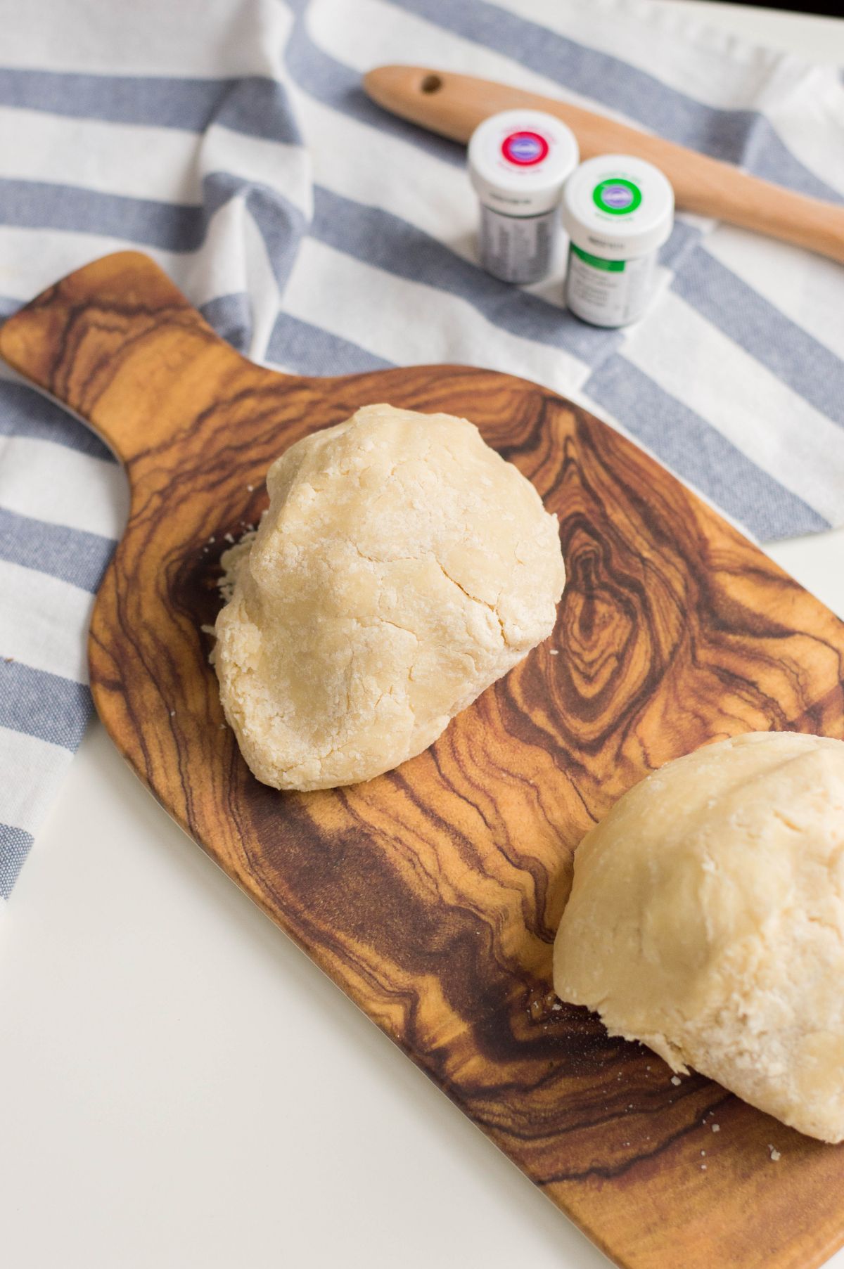 A vertical image of two formed dough on a wooden chopping board.