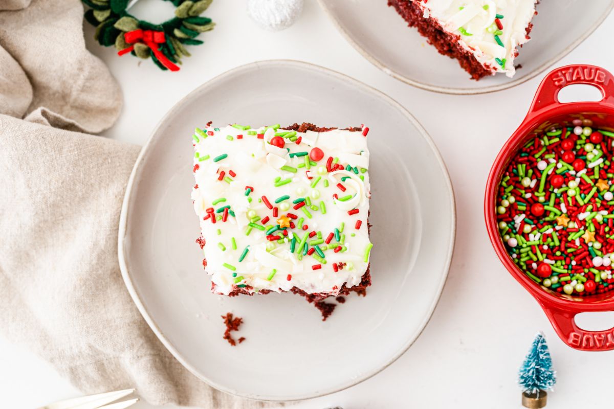 A horizontal overhead shot of a square slice of Christmas Poke Cake on a small white serving plate.