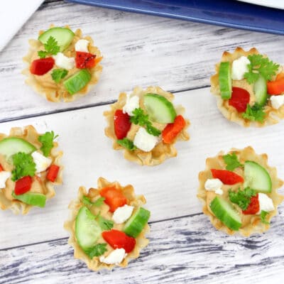 Overhead view of 6 bite sized appetizer cups filled with fresh veggies and hummus