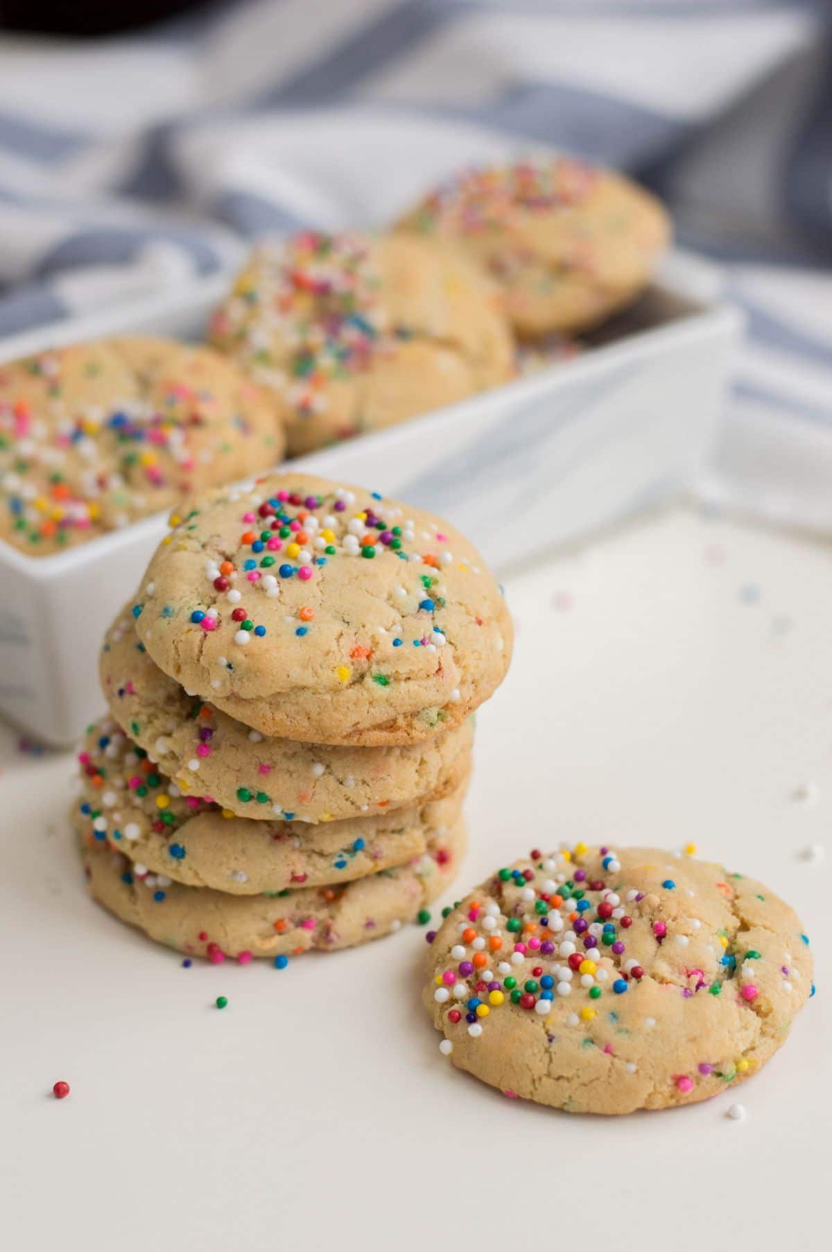 A vertical image of Funfetti cookies, a stack of 4 cookies and a single cookie beside the stack.