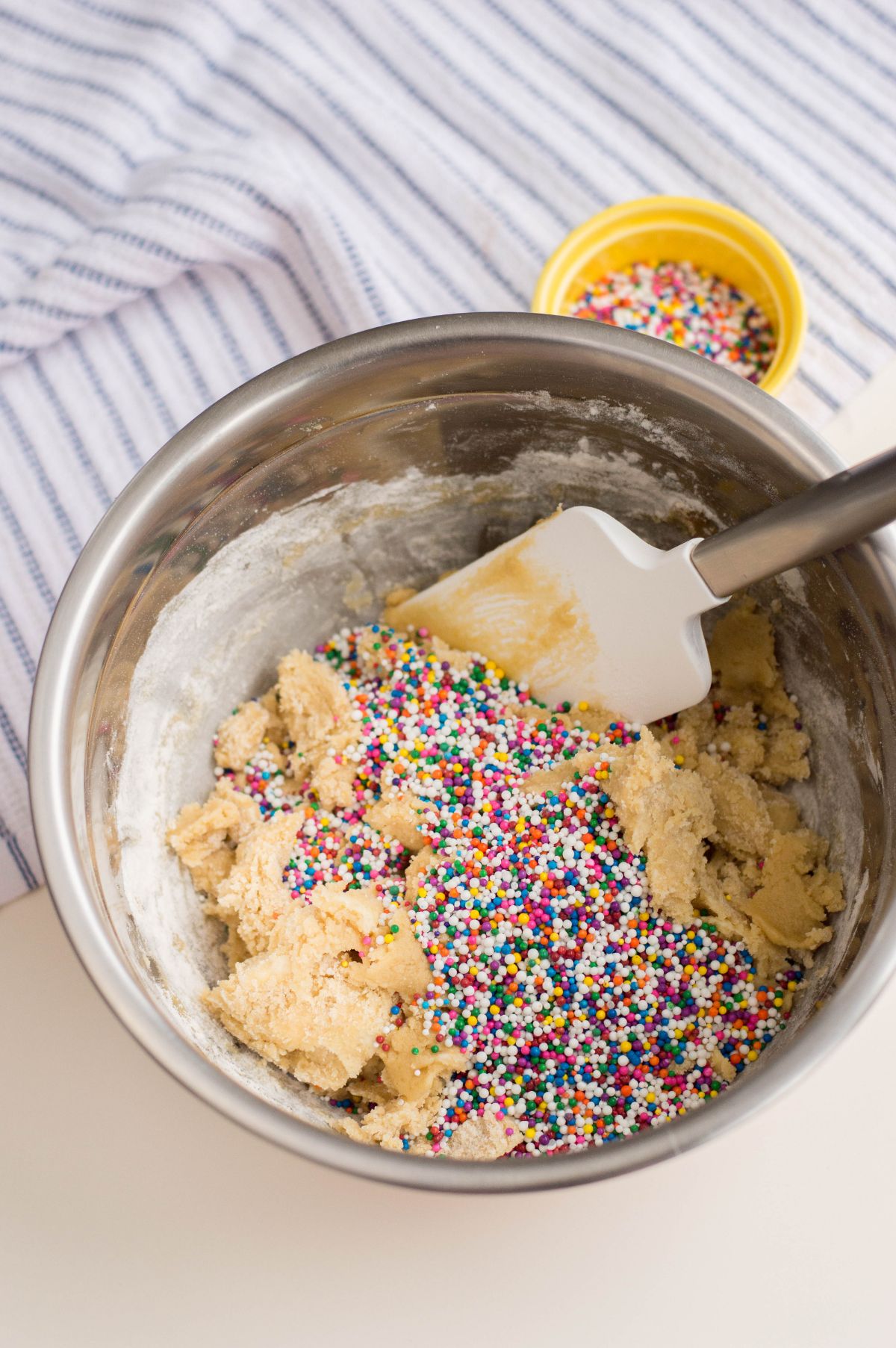 Sprinkles added on the dough mixture in a mixing bowl.