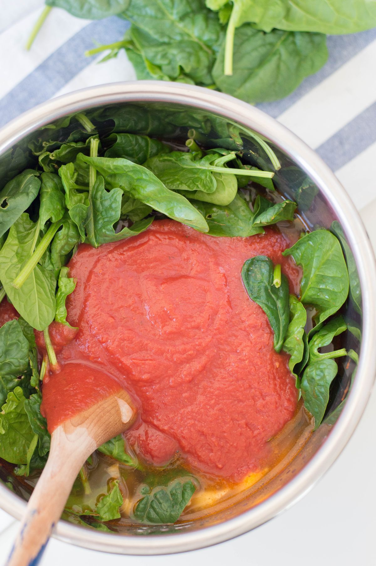 Fresh spinach and tomato paste added to the sauteed onion and garlic in the instant pot.