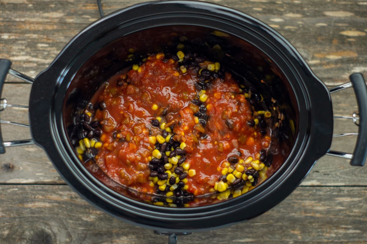 Salsa, beans, and corn on top of the chicken inside the slow cooker.
