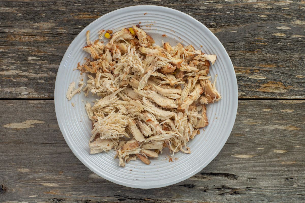 Shredded chicken breasts on a white plate.
