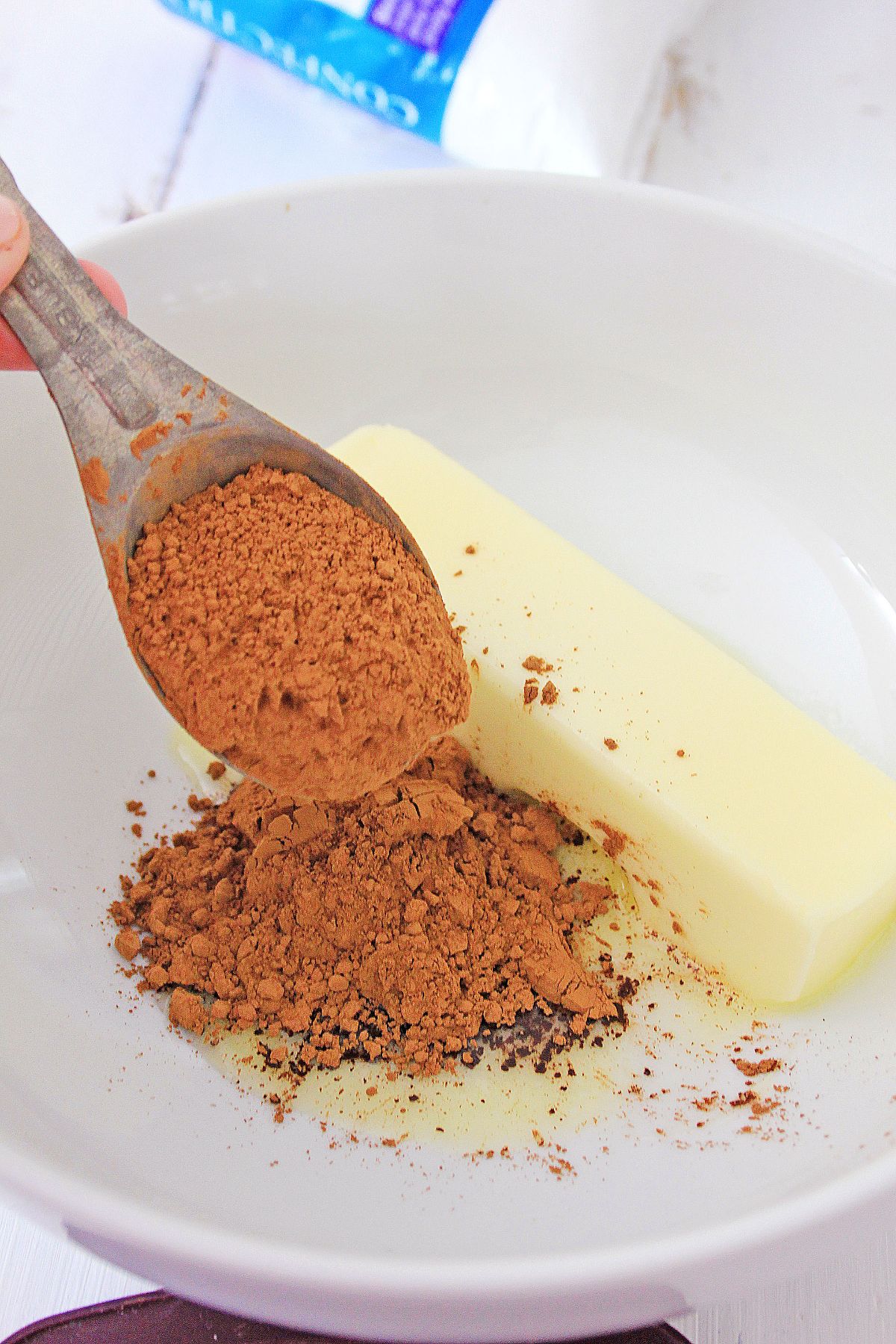 Ingredients  being combined in a white mixing bowl to make an icing.