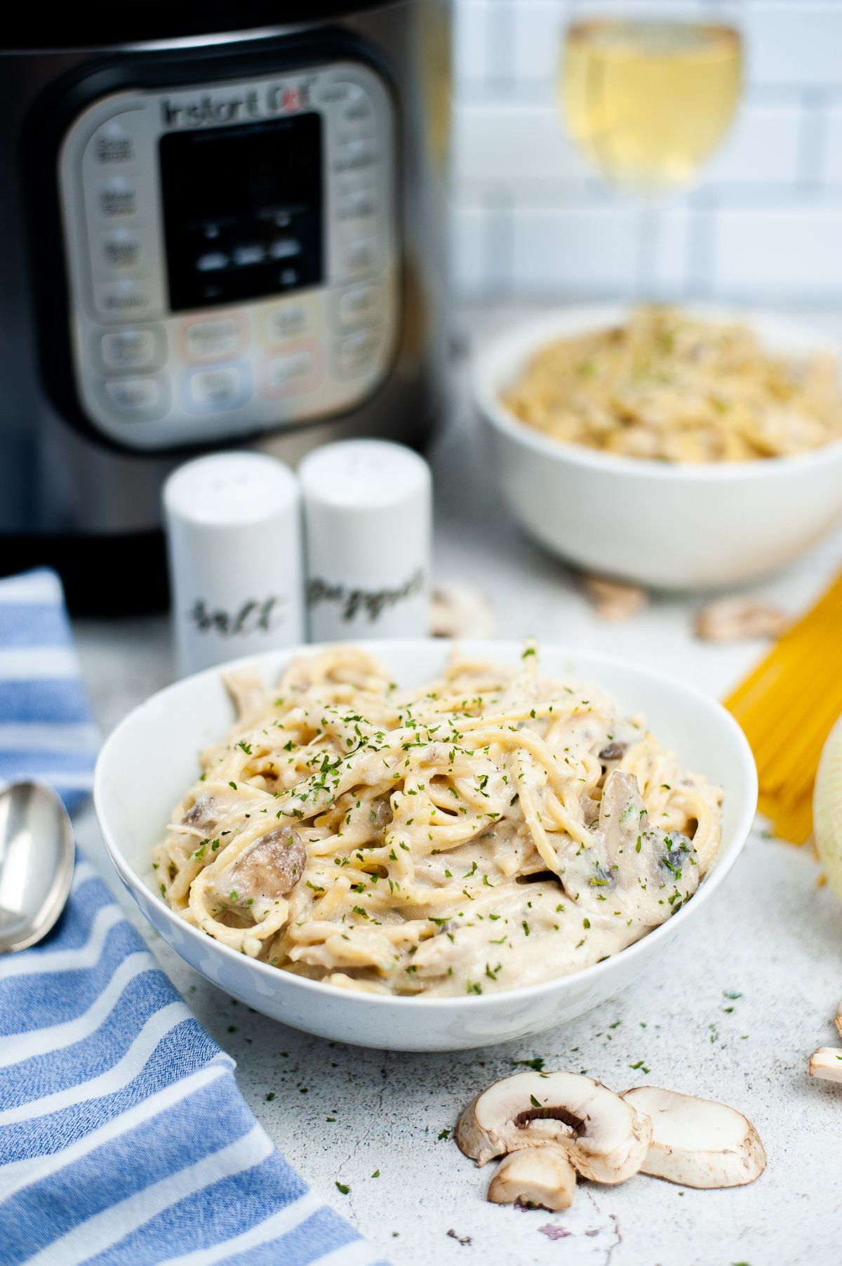 Instant Pot Chicken Tetrazzini in white serving bowl with the instant pot blurred in the background.