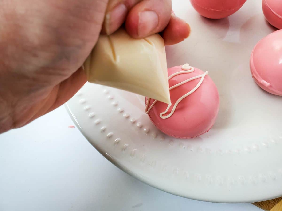 Strawberry bomb being drizzled with melted white chocolate.
