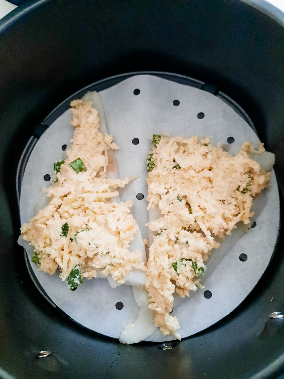Coated cod pieces in an air fryer.
