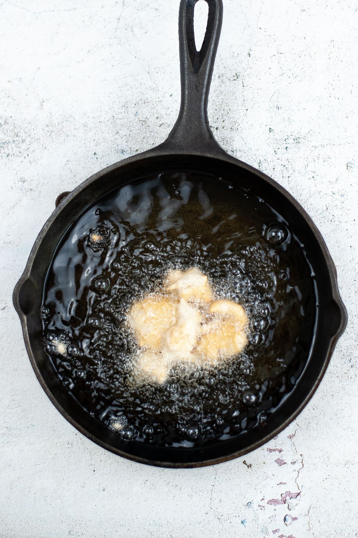 Fritters being fried in a skillet.