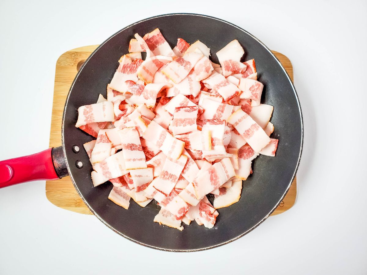 Bacon being cooked in a skillet.