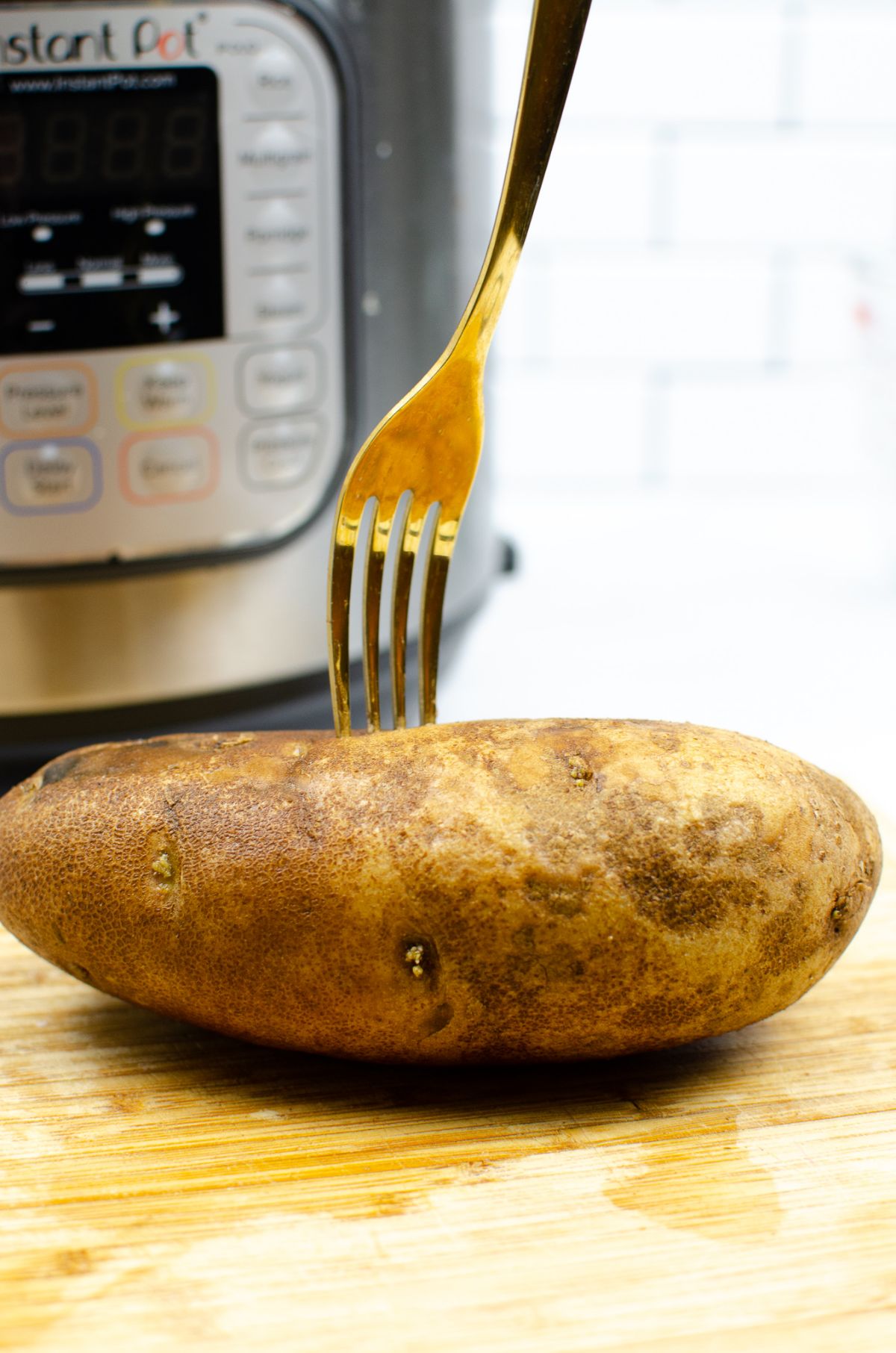 A whole potato, being poked by a fork.