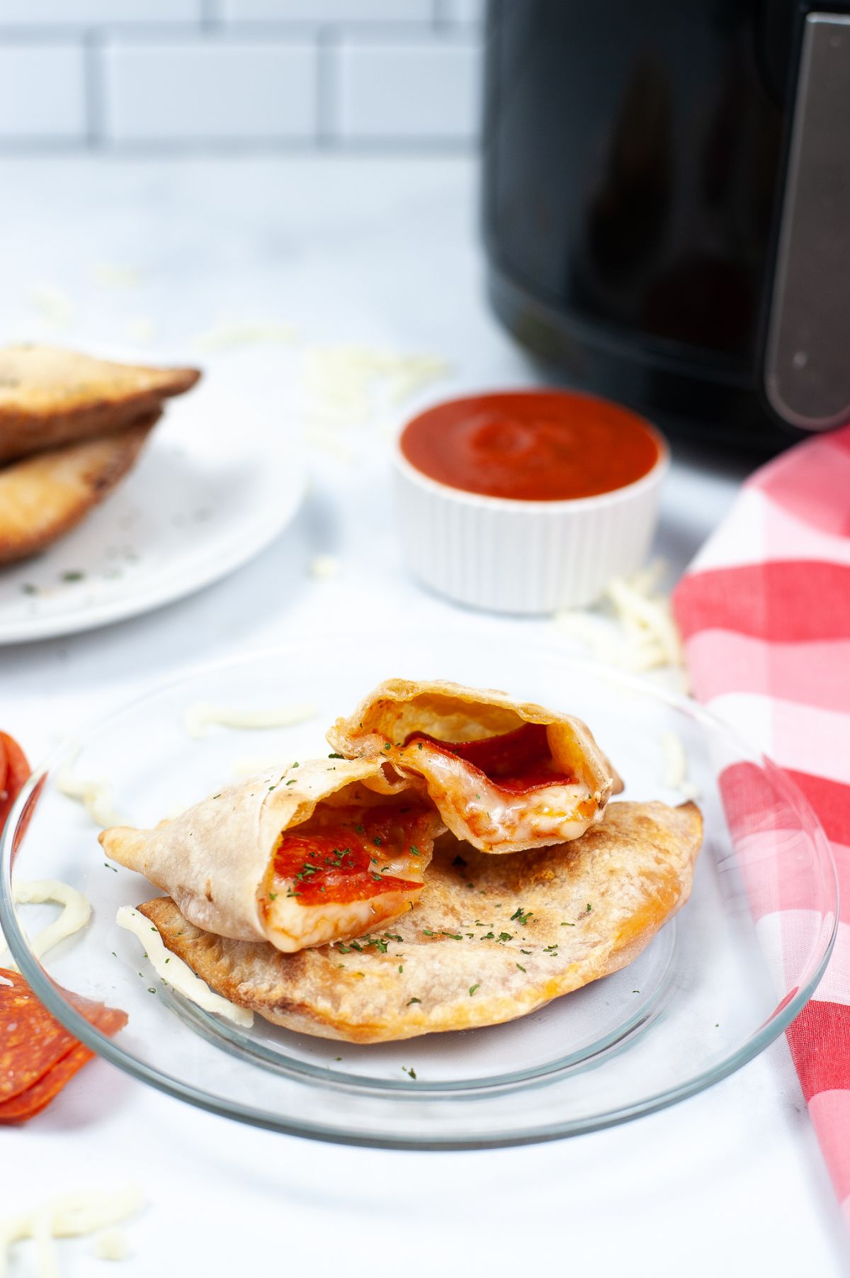 A serving of 2 pieces of Air Fryer Calzone where one is halved on top of the other piece showcasing the melted cheese filling.