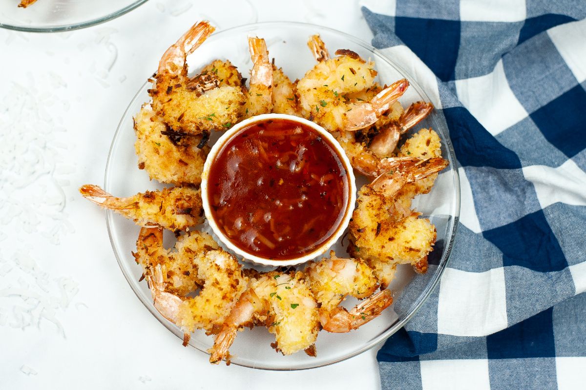 Overhead shot of Air Fried Coconut Shrimp on a glass serving plate with a sauce in the middle.